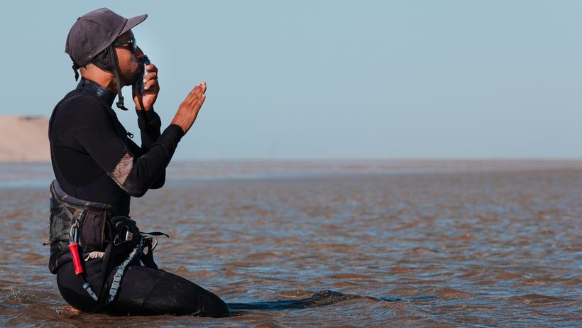 Instructor kneeling in the lagoon, coaching a student over the radio
