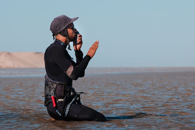Kitelehrer coacht einen Schüler per Funk vom Strand aus